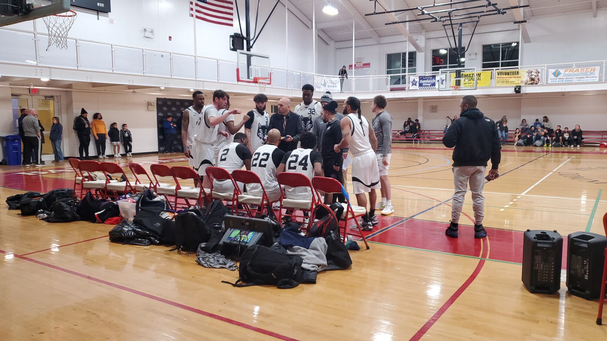 Mike Gillespie, #55 of the Massachusetts Wolves, passionately strategizing with his team in a timeout huddle, displaying leadership and focus, during a critical game pause against 413 Elite.